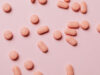 Hellrote Pillen auf rosafarbenem Hintergrund
